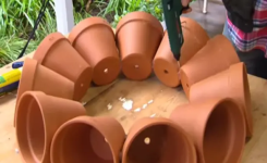 Il place 11 pots de fleurs en cercle sur une table et les colle ensemble